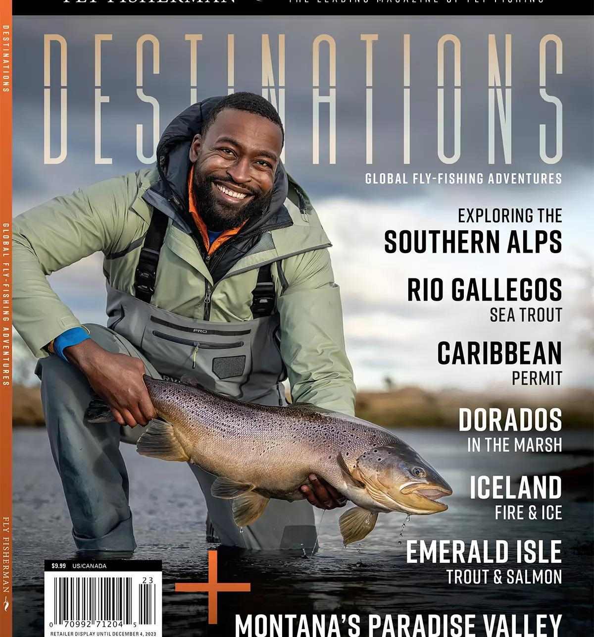 A wader-clad fly angler kneeling and holding a large brown trout, smiling at the camera.