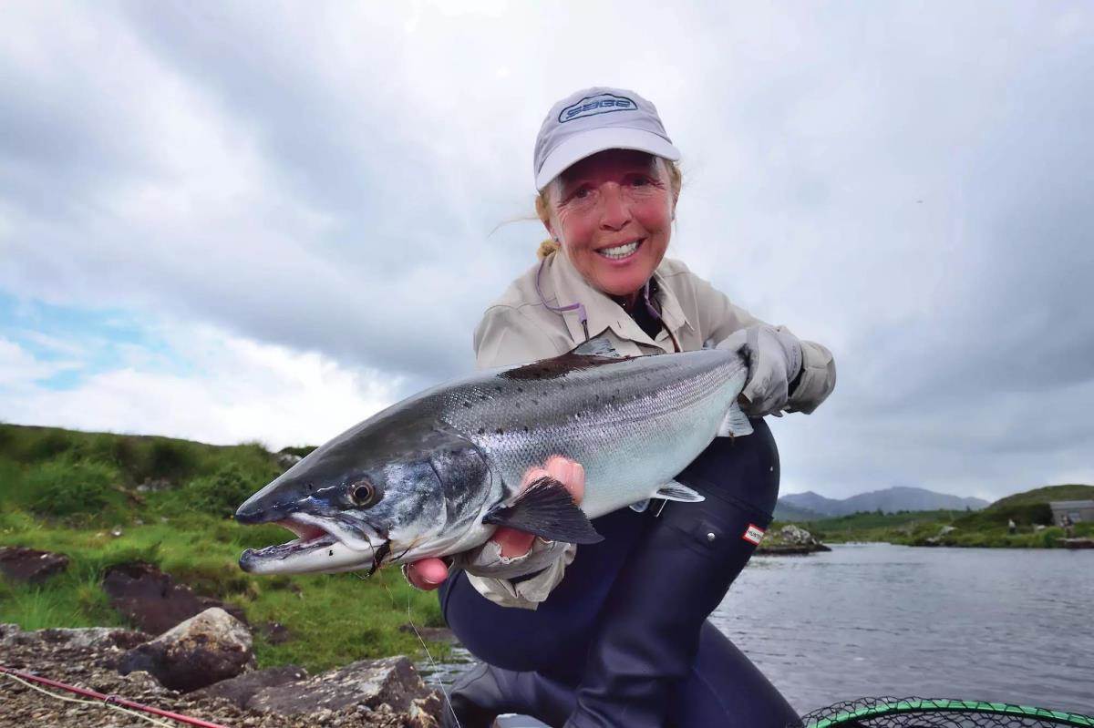 A fly angler holding a chrome Atlantic salmon for the camera. 