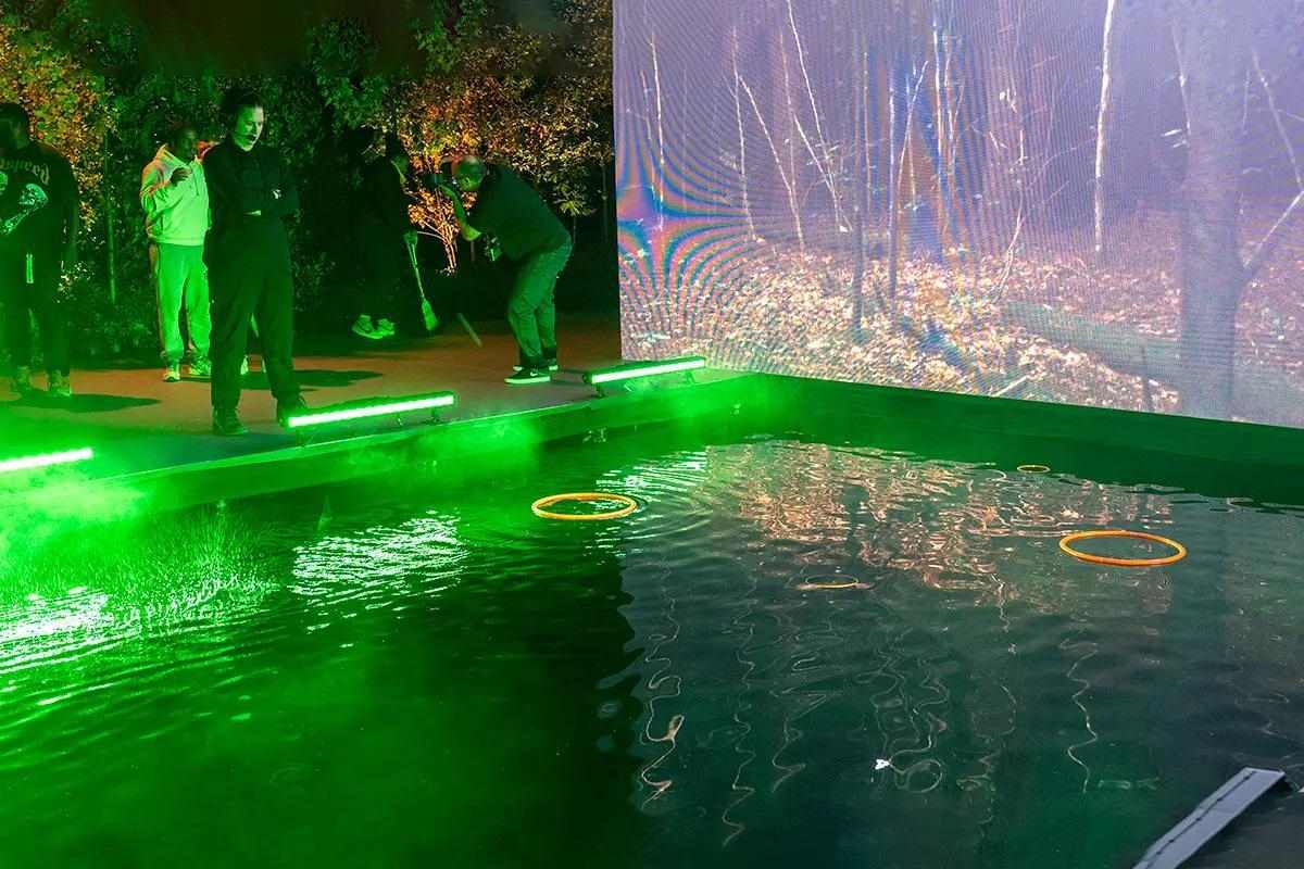 A fly-casting competition pond lit up by neon lights and fog.