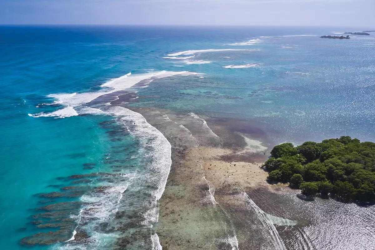 The tapered end of a tropical island, waves lapping ashore into the distance.