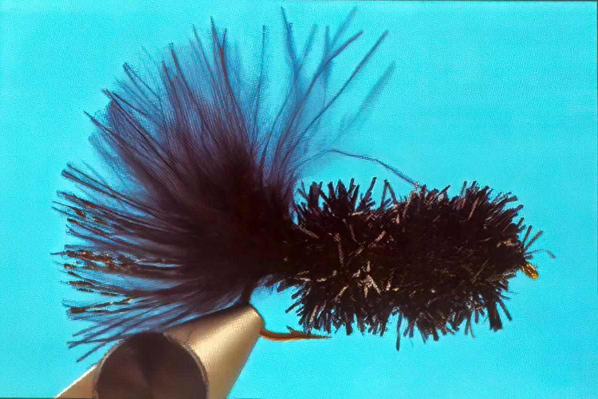 A short stubby black Woolly Bugger variation in a vise. 