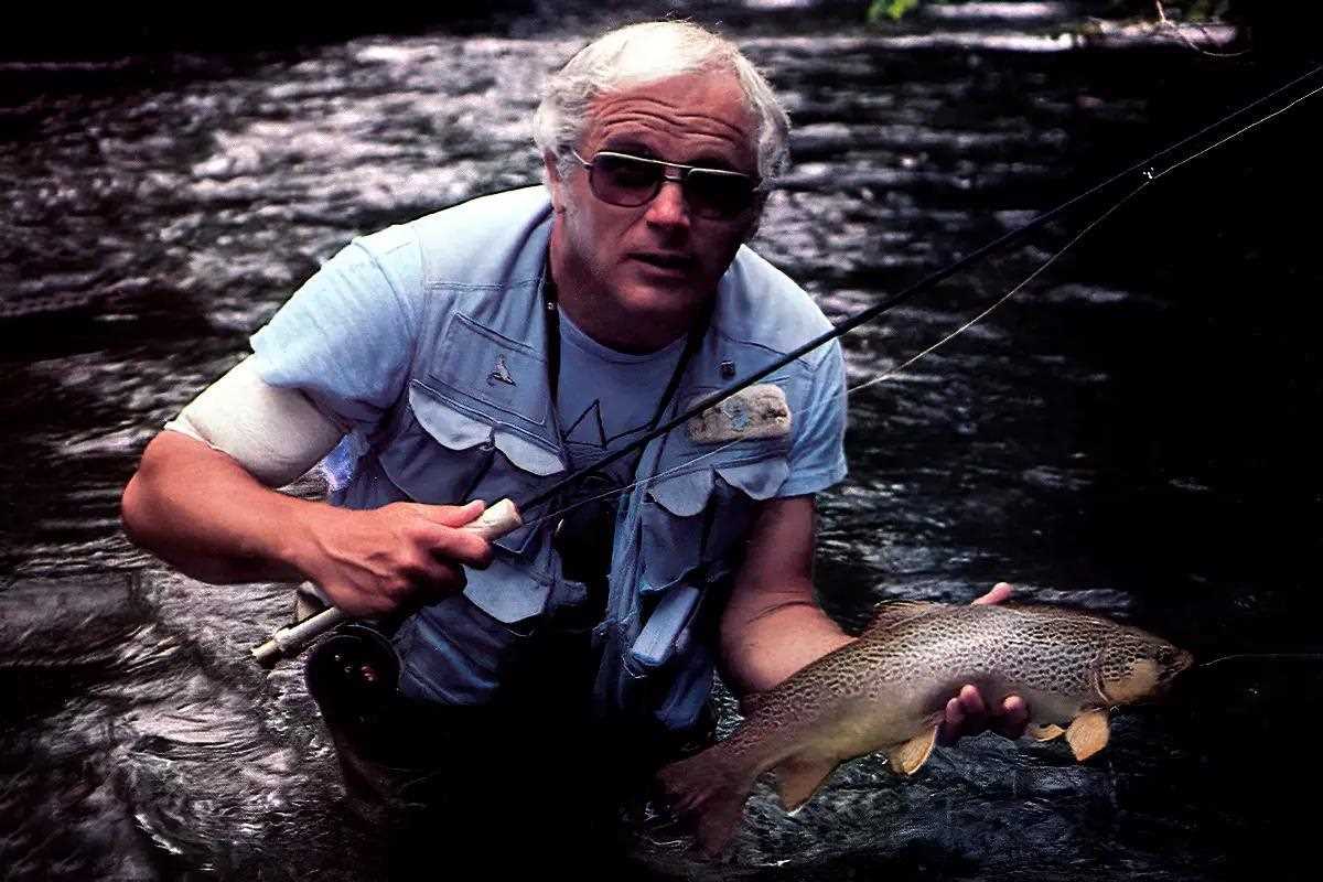 A fly angler holds a nice brown trout for the camera. 