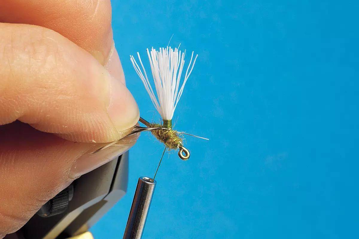 A small dry fly in a vise, in the tying process.
