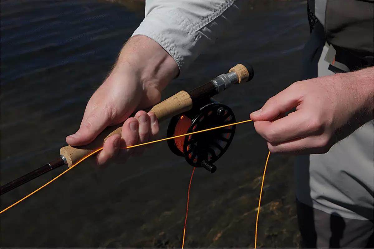 A man's hands holding a fly rod, demonstrating a fly retrieve.