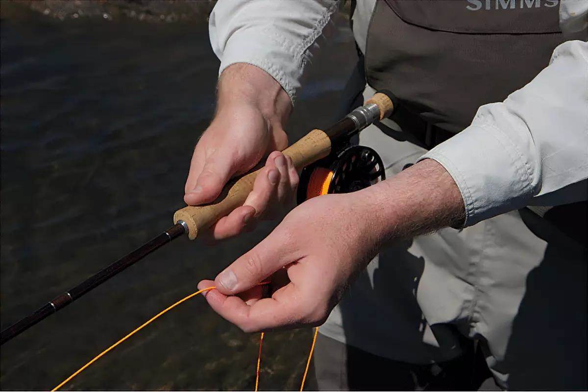 A man's hands holding a fly rod, demonstrating a fly retrieve.